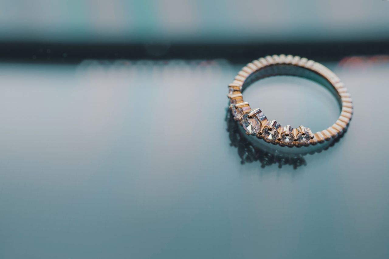 A seven-diamond wedding band made of yellow gold against a reflective background