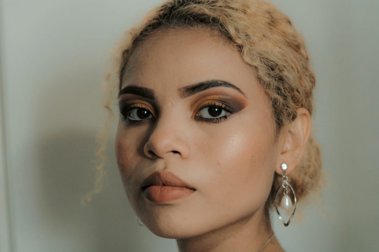 a woman looking into the camera and wearing silver earrings with a dangling pearl