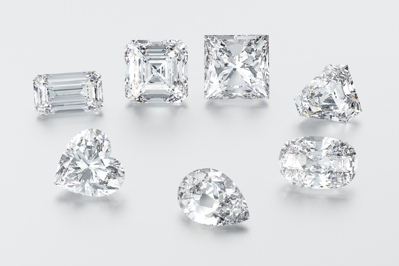 A variety of diamond cuts sit on a white surface.