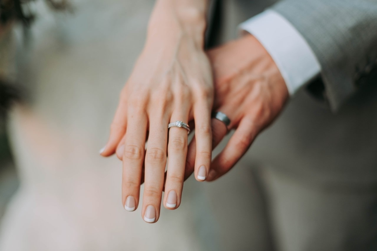 a man and woman’s hands wearing wedding rings