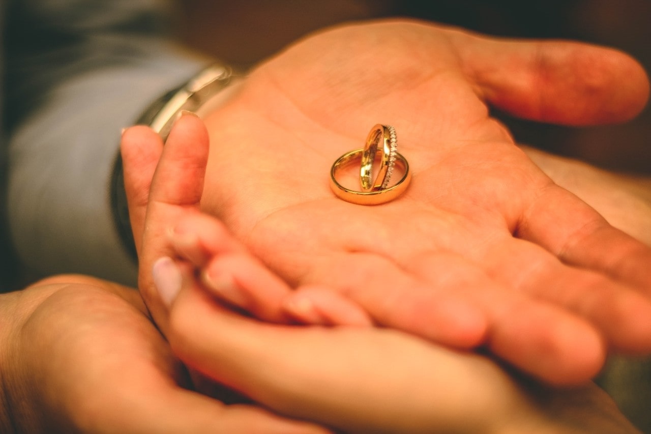 two gold rings held in the palm of a man’s hand