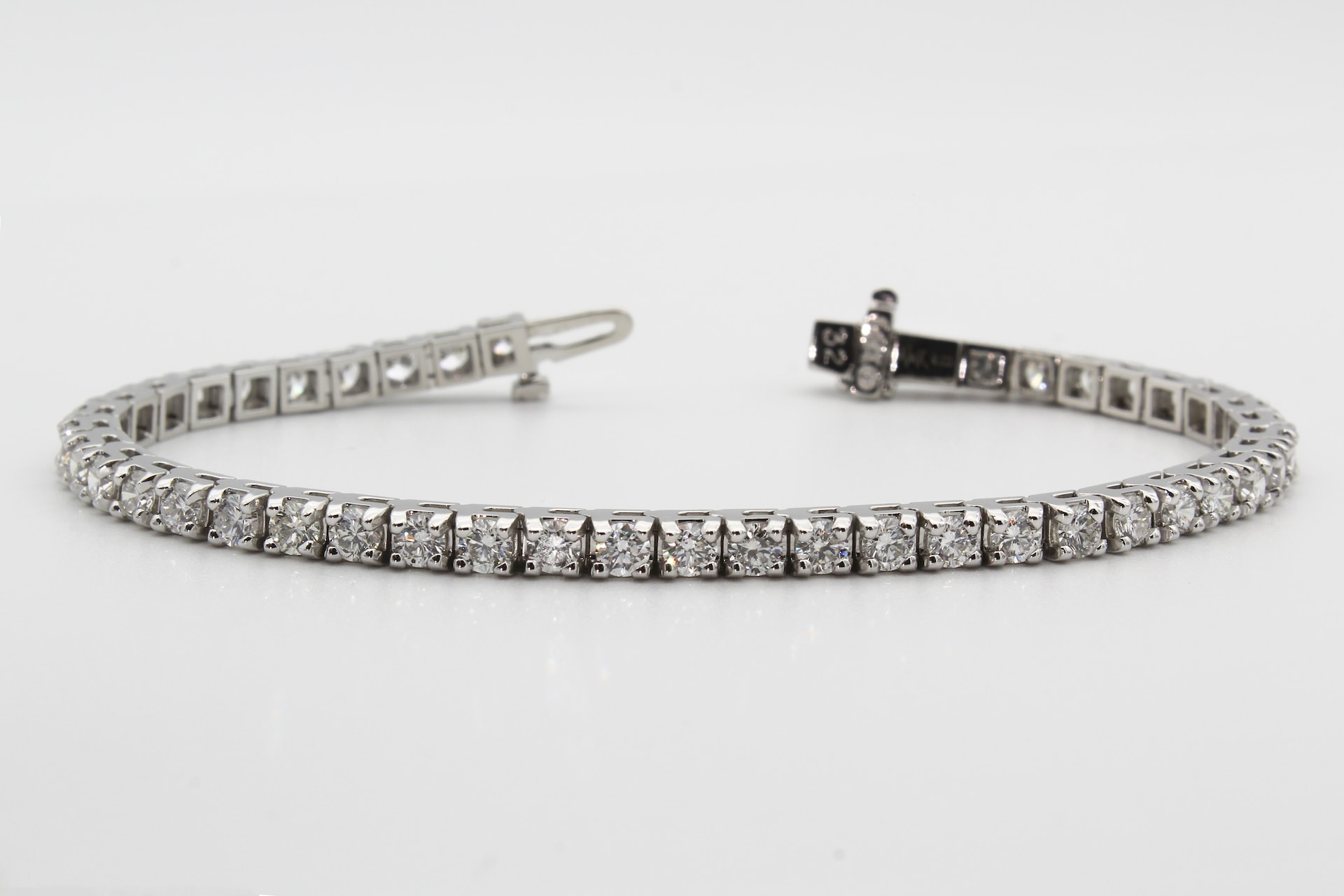 a diamond and platinum bracelet on a gray background