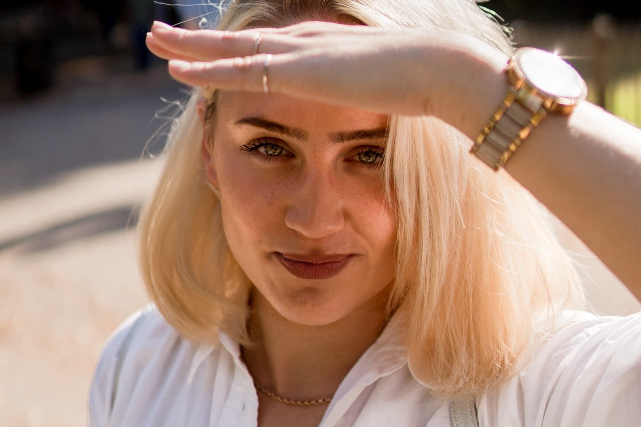 a lady wearing a luxury watch shielding her eyes from the sunlight