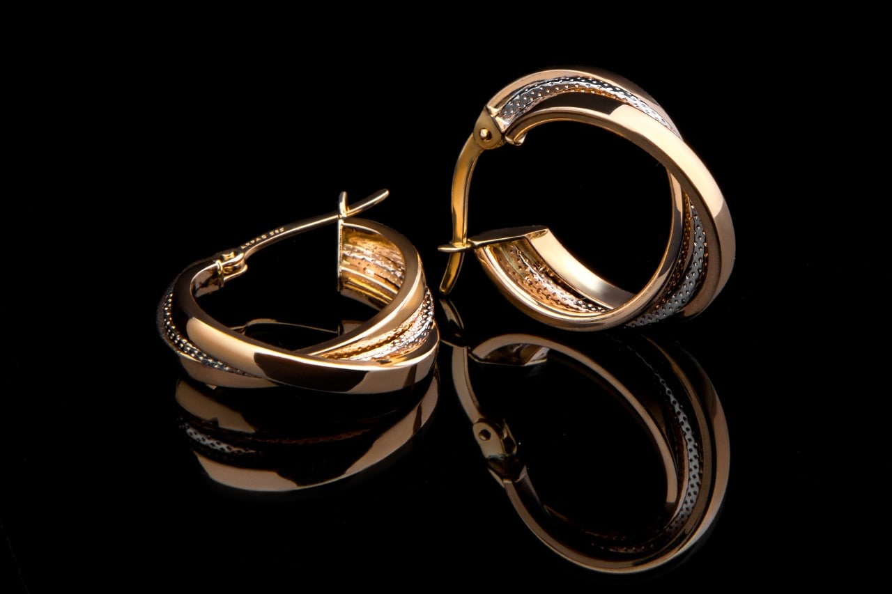 A pair of mixed metal hoop earrings against a black background