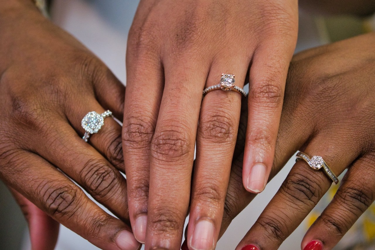 three ladies’ hands wearing different diamond engagement rings