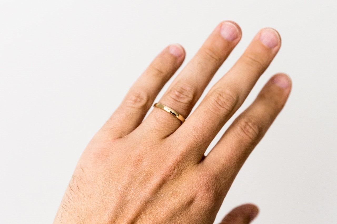 man’s hand wearing a gold ring