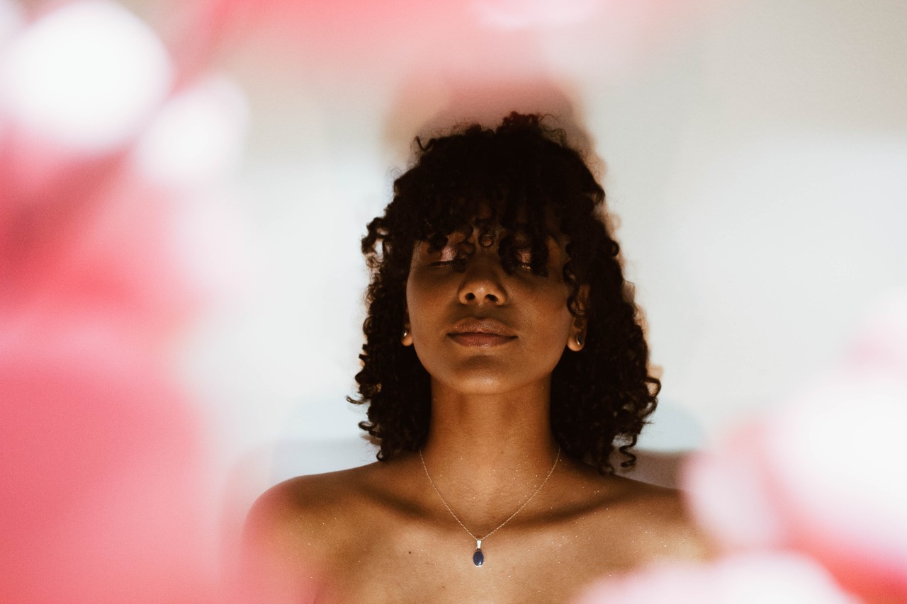 a woman meditates while wearing an onyx pendant.