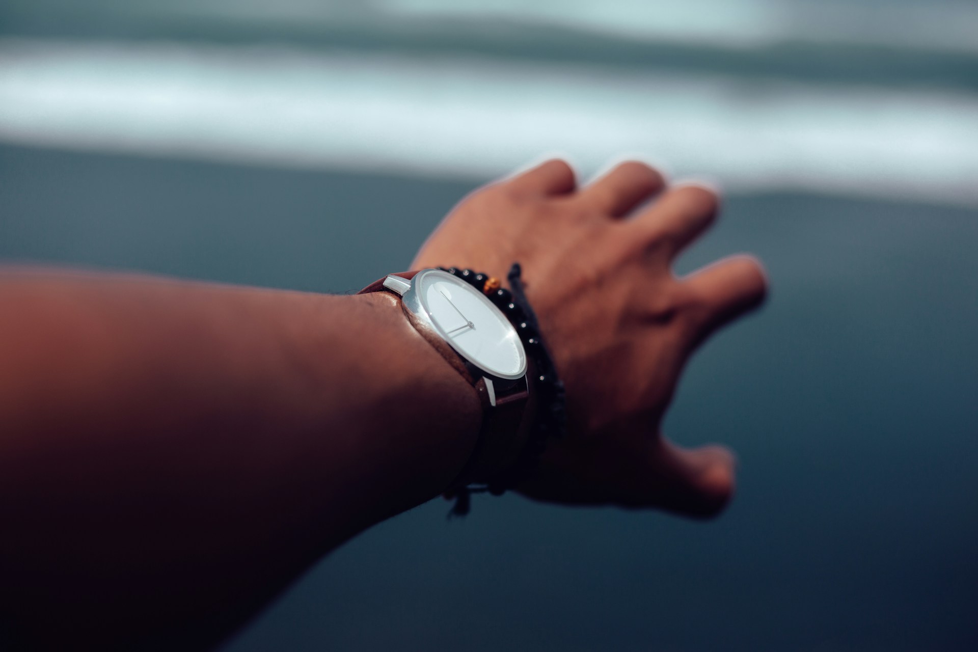 a man’s hand wearing a watch with a gray background
