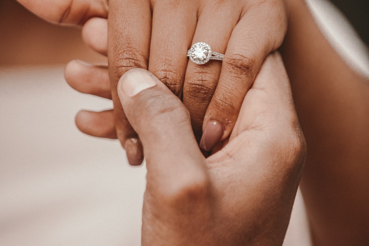 A woman’s hand shows off a round-cut diamond halo engagement ring
