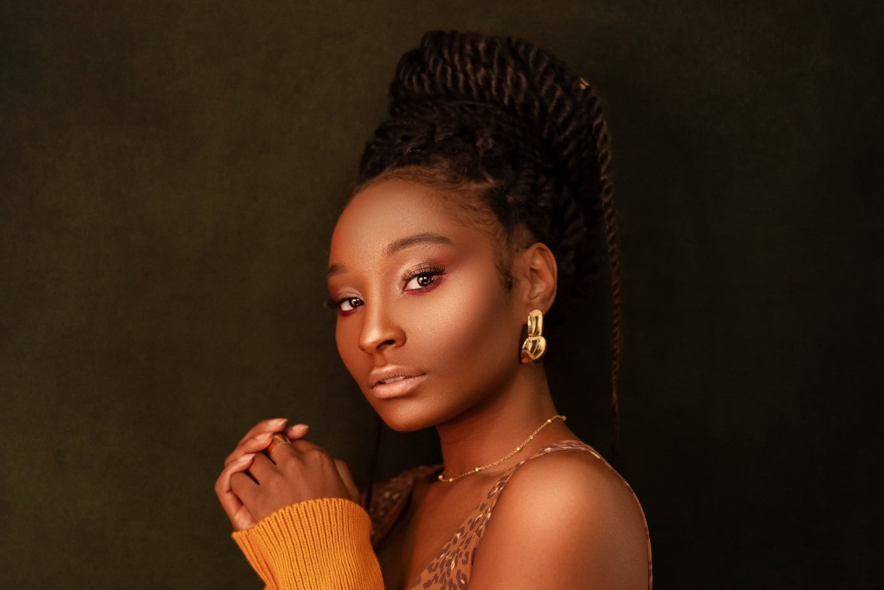 a woman looking into the camera and wearing a pair of large, sculptural yellow gold earrings