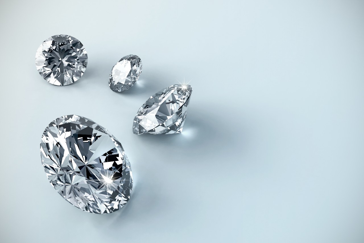 A group of round-cut diamonds sit on a light blue surface.