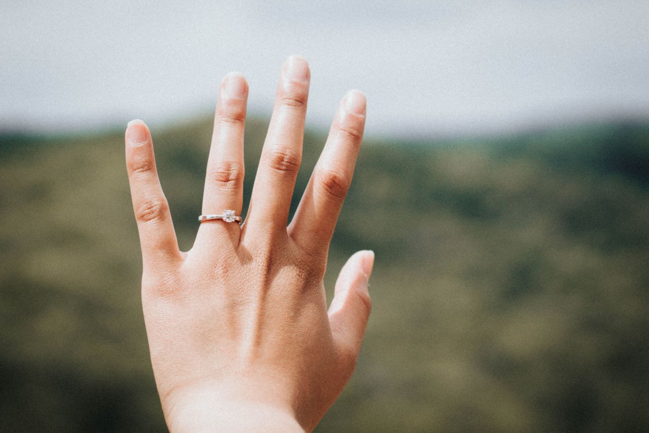 a lady’s hand wearing a diamond solitaire ring