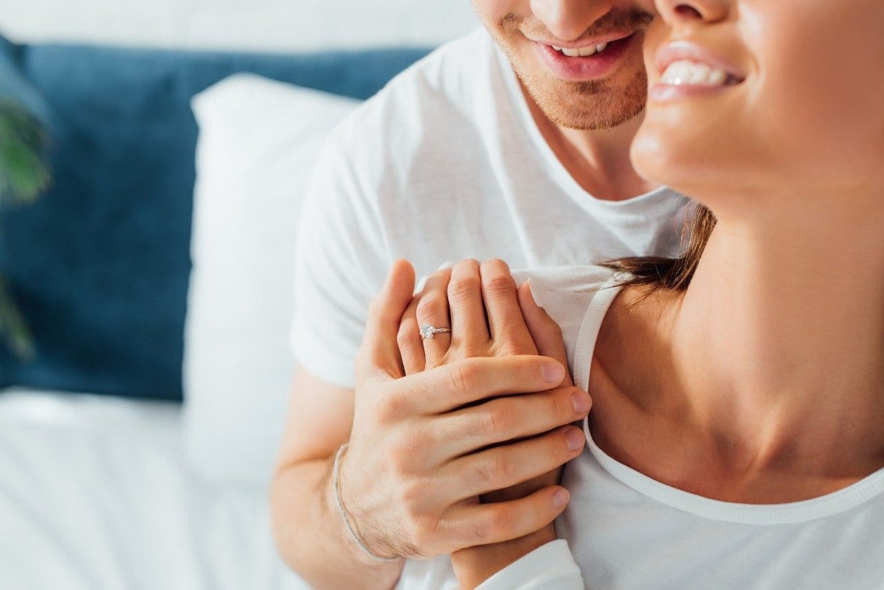 woman wearing a gold engagement ring and holding a man’s hand