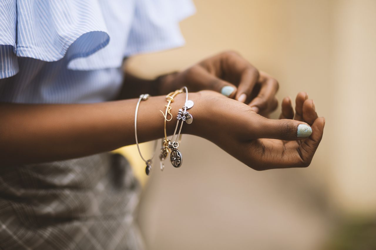 A woman’s wrist adorned with mixed metal bracelets.