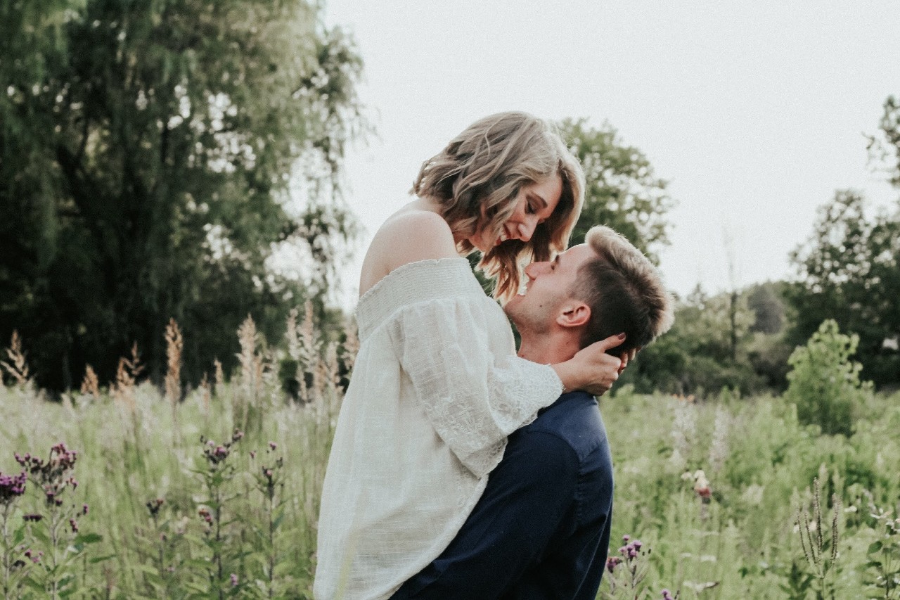 a romantic couple embracing in a green field