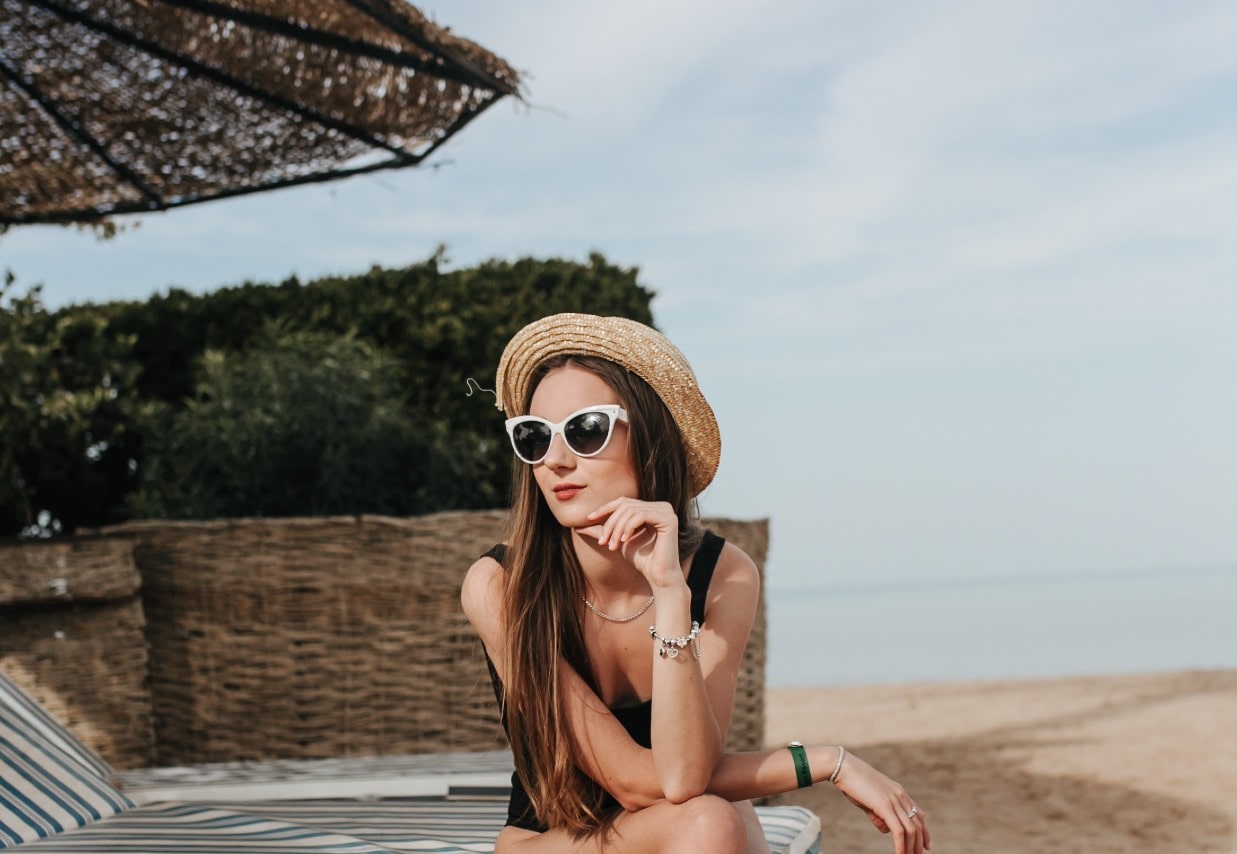 A woman lounges at the beach with a necklace and three bracelets