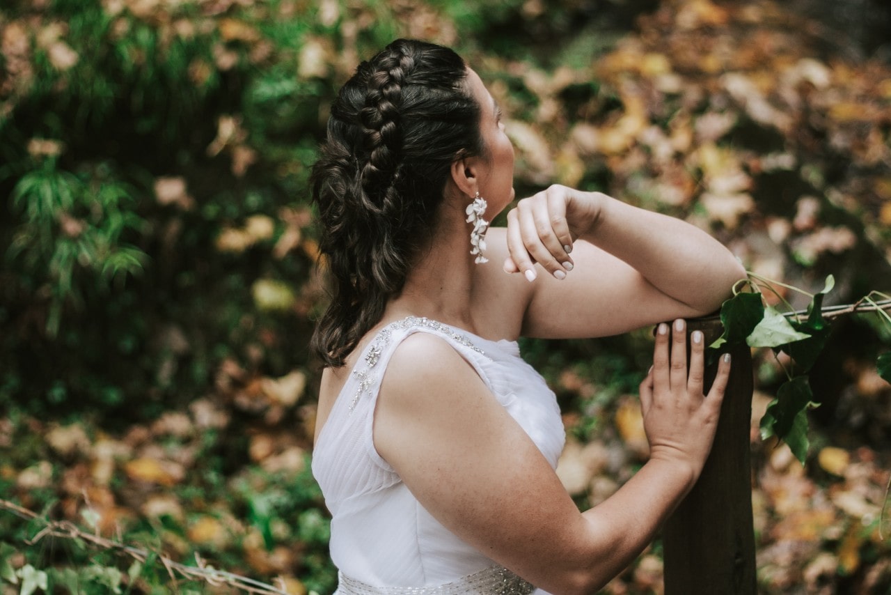 a bride facing away from the camera in a forest during the fall