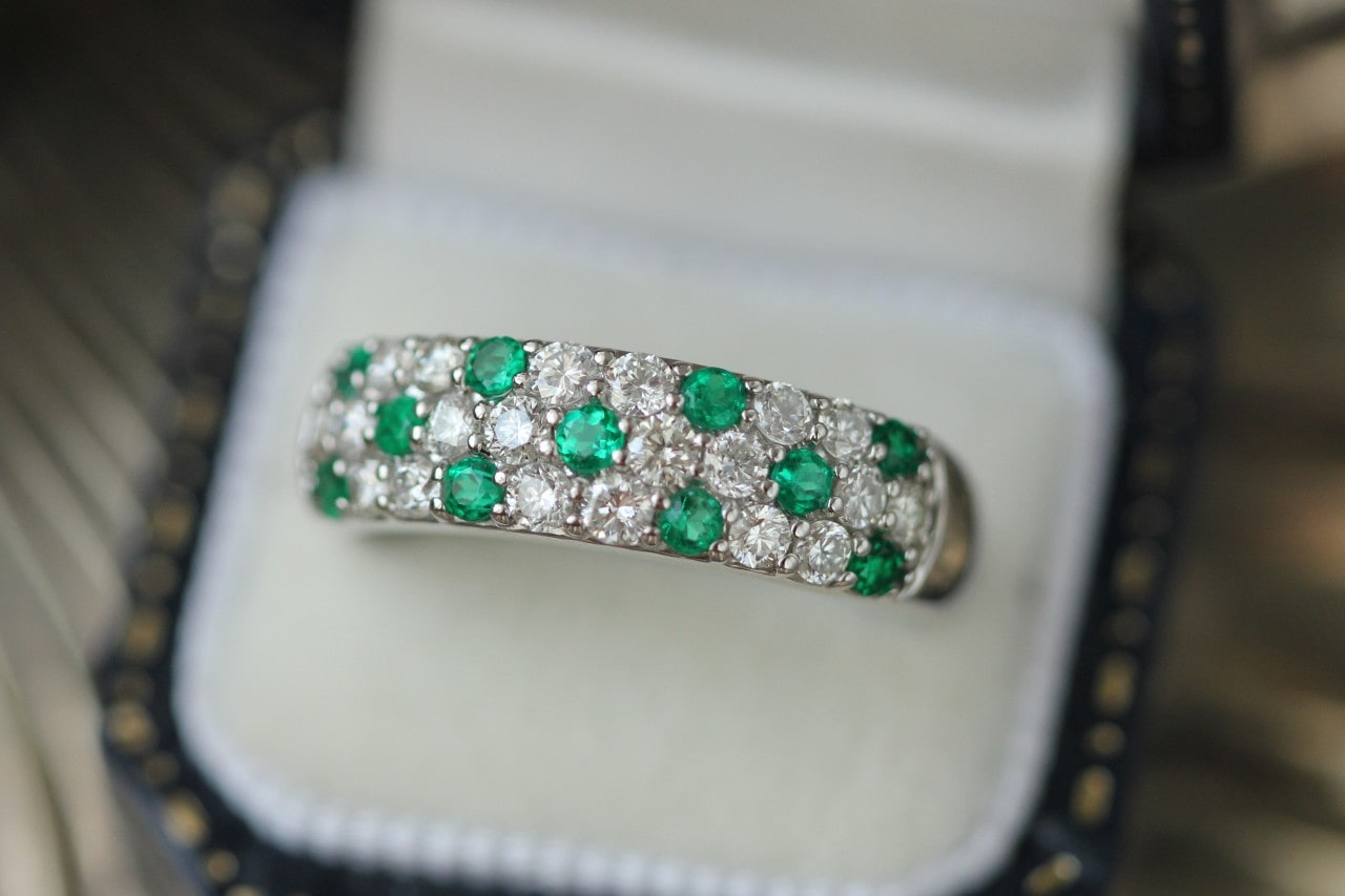 a diamond and emerald pave wedding band in a ring box