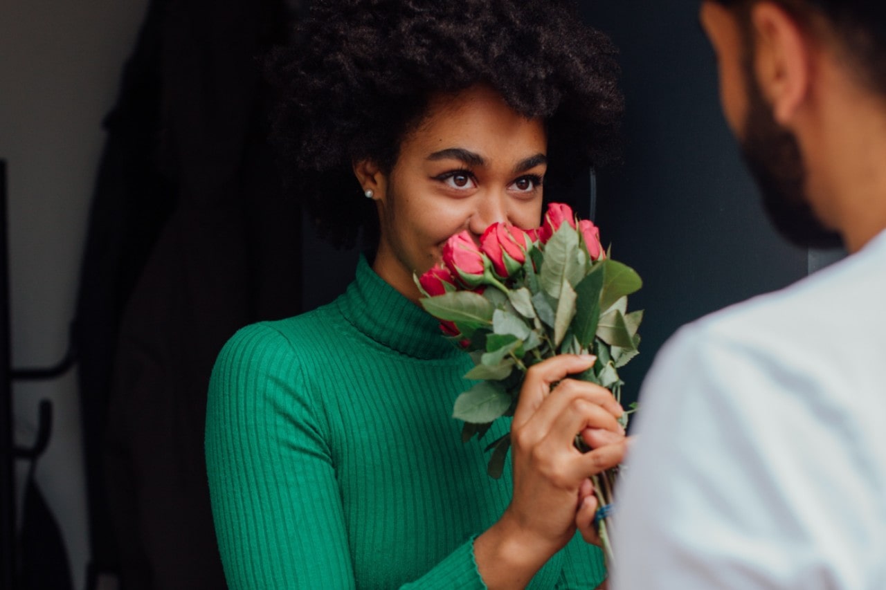 A woman sniffs a bouquet of roses, trying to figure out a clue during a scavenger hunt.