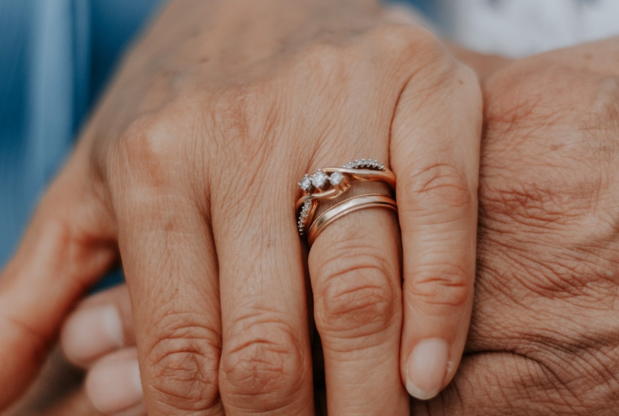 a hand wearing two bridal rings together