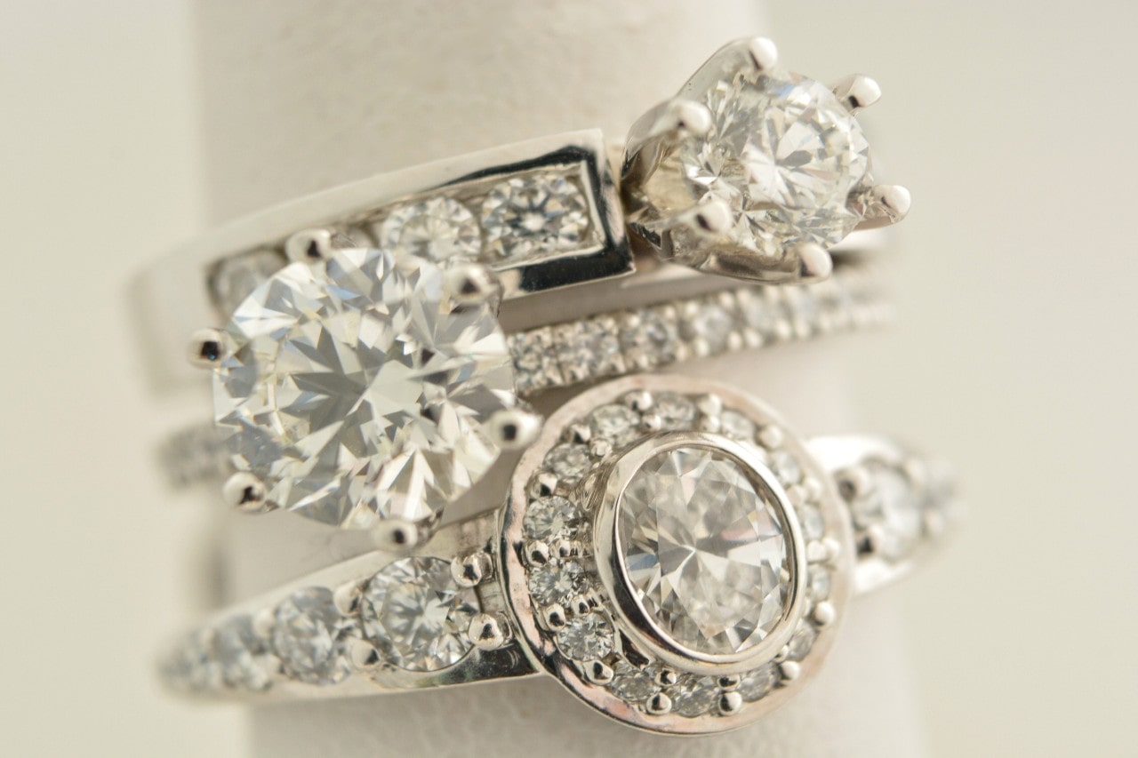 A close-up of three elegant diamond rings stacked, each featuring sparkling stones in various cuts and settings.