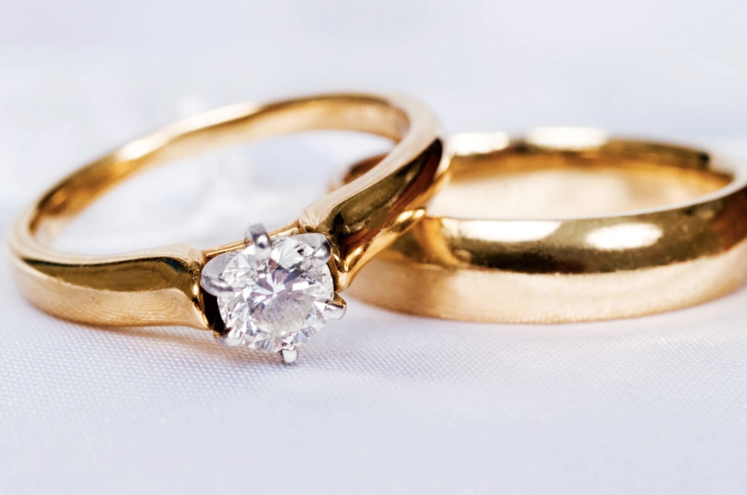 A yellow gold engagement ring with a round-cut stone stacked on a yellow gold wedding band.