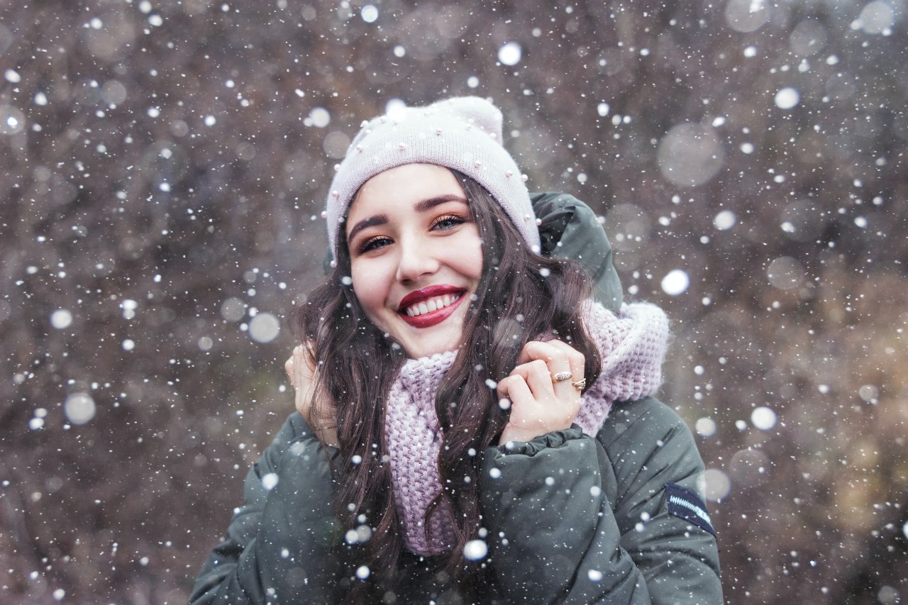 A young woman wears fashion rings while bundled up in the middle of a mild snowstorm outside